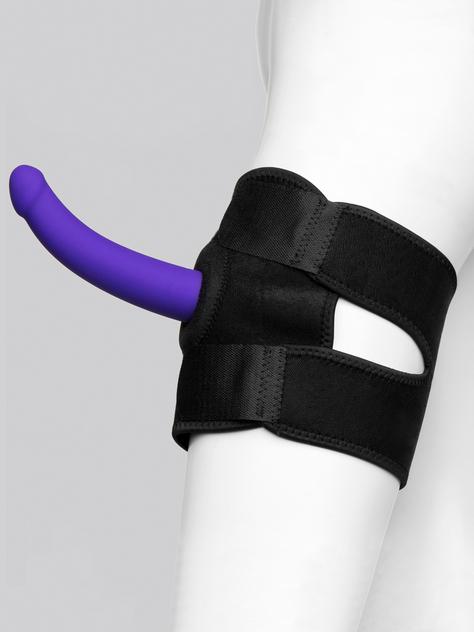 A black neoprene leg harness with two large Velcro straps is attached to a mannequin leg with a purple dildo positioned in the center