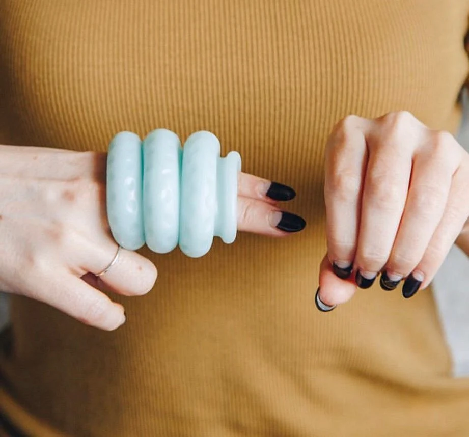 Three blue silicone rings are stacked atop white manicured fingers